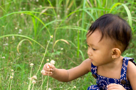 lifestyle portrait of cute asian girl playing in the meadow on a beautiful dayの写真素材