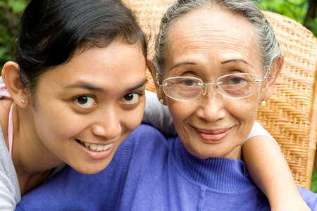 portrait of cheerful asian young woman embracing her old mother lovingly