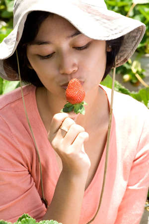 portrait of asian young woman kissing an organic strawberryの写真素材