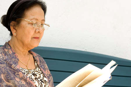 portrait of asian old woman enjoy reading a literature outdoorの写真素材
