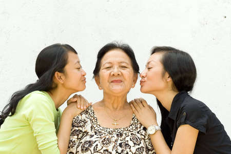 asian family portrait of two teen girls show their love to their old grandmother