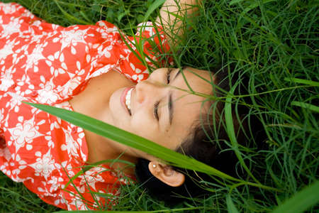 relaxing asian young woman lying on the green grassの写真素材