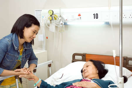 asian granddaughter visit her sick grandmother having bed resting in inpatient treatment at the hospitalの写真素材