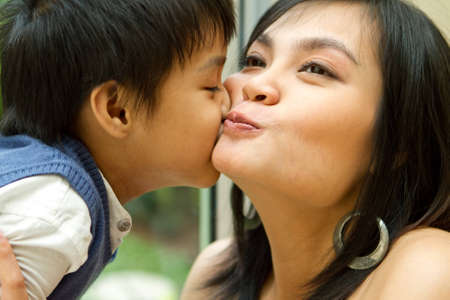 Closeup portrait of asian ethnic boy kiss his happy motherの写真素材
