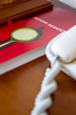 Desk of a hotel with room service list and telephoneの写真素材