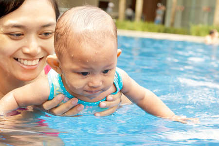 Asian ethnic mother teach baby girl to swimの写真素材
