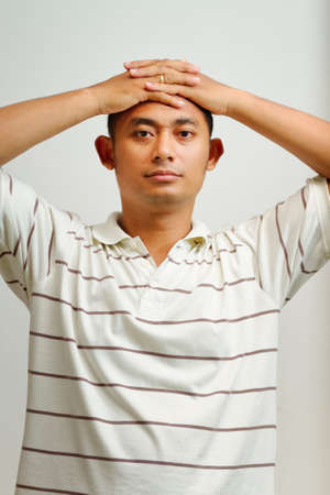 portrait of asian ethnic young adult male placed hands on the head, relaxingの写真素材