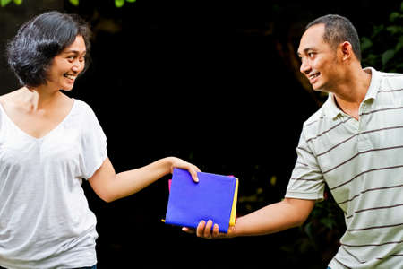 ethnic asian students hand over stack of books