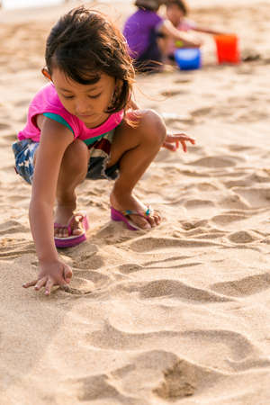 asian ethnic little girl writing on the white  beach sandの写真素材