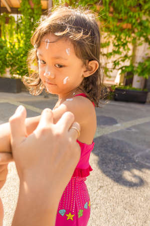 Mother Hand Putting Sunblock Cream on the Face of a Child Before Swimmingの写真素材
