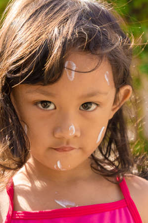 Closeup Face of Asian Little Girl with Sunblock Lotion Before Swimmingの写真素材