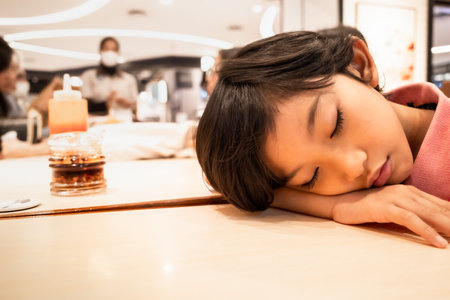 An Asian boy falling asleep on the table while waiting for dinner at a restaurantの写真素材