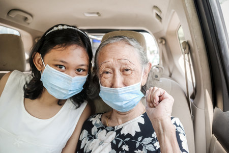 Asian teen girl and grandma wearing face masks inside a carの写真素材