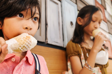 Southeast Asian children, boy and girl enjoy eating ice cream cones together at mallの写真素材