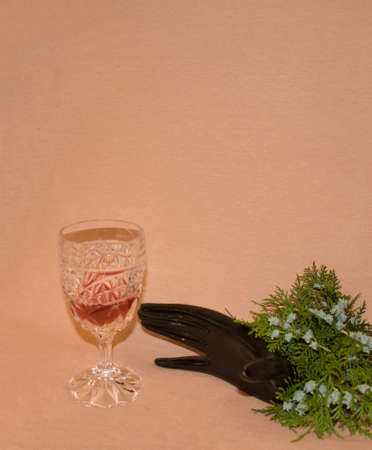 Can I have a glass of wine? A hand is stretched out of a pine tree to reach for the crystal glass. Celebration card. Minimalist concept.の写真素材