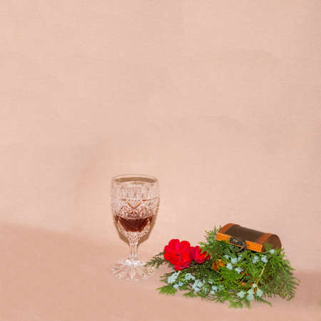 New Year's and Christmas card with a crystal glass of wine and pine branches coming out of a wooden box with a red flower that gives a celebratory impression. Minimalist conceptの写真素材