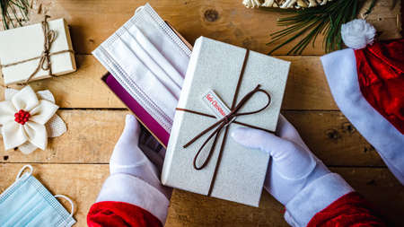 Santa Claus hands in white gloves holding Safe Christmas presents and a mask