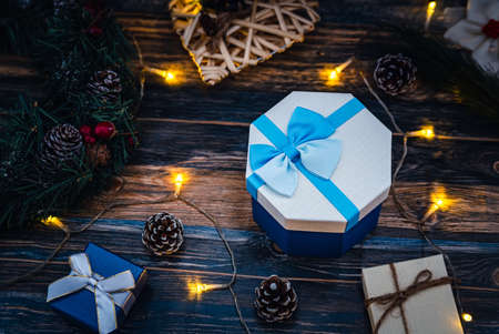 Christmas gifts over a wooden background with gift boxes, Christmas balls, branches, tree, and...
