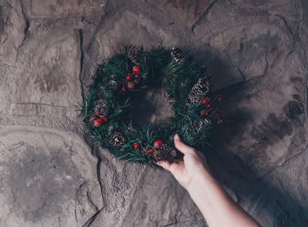 Woman decorating and preparing her home for christmas. Woman decorating the fireplace with gifts, and christmas decoration such as garland, lights and christmas wreath.の写真素材