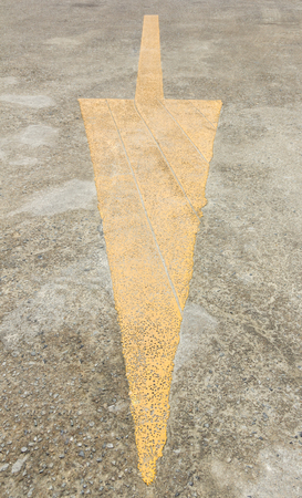 Yellow down arrow sign on the roadの写真素材