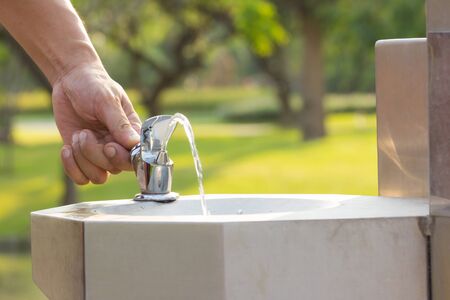 hand pushing button of drinking water faucet at public parkの写真素材