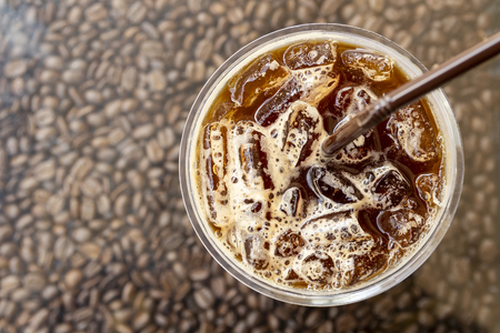 top view plastic glass of iced black coffee on coffee beans backgroundの写真素材