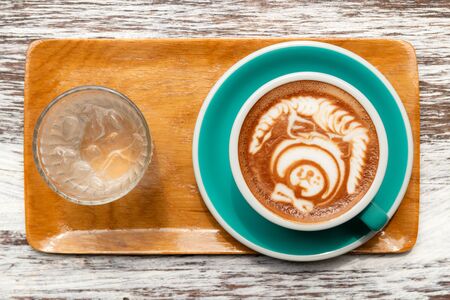 top view of cup mocha coffee with latte art and glass of water on wooden table backgroundの写真素材