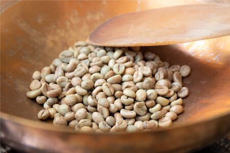 Close up of green coffee beans in a brass pan