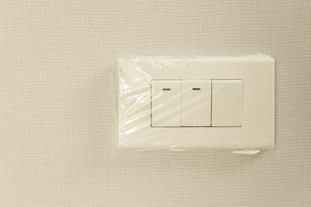 new light switch  in plastic wrap on white wallpaper homeの写真素材