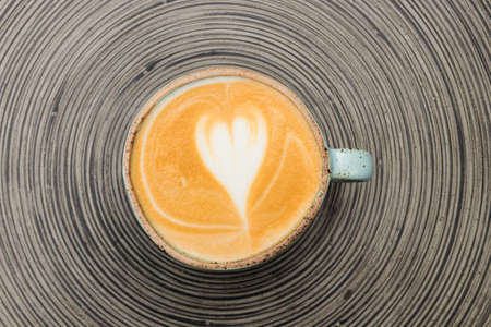 cup of coffee with latte art foam on wooden table. top view