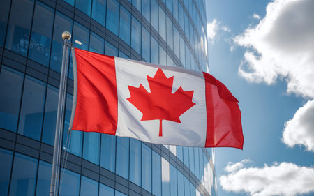 Canadian flag waving in the wind against modern office building.の素材
