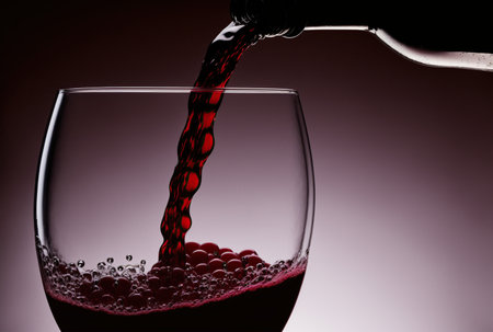 Pouring red wine into a glass on a dark background, close-upの写真素材