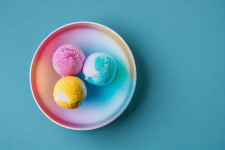 Top view of colorful ice cream balls in bowl on blue background. generative aiの素材