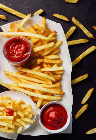 French fries with ketchup on a black background. Top view. generative aiの素材