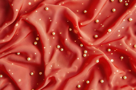 Red satin background with golden pearls, close-up.の素材