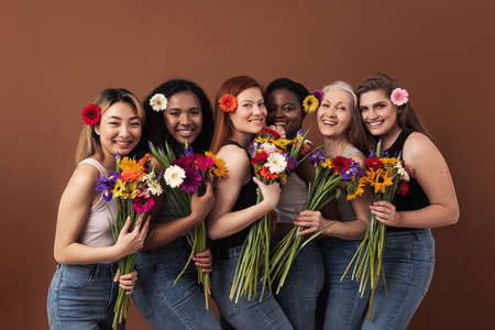 Six smiling women of different ages looking at camera in a studio. Happy diverse females with...
