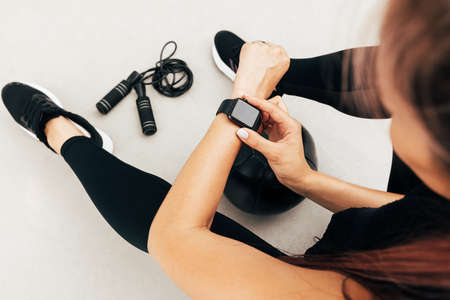 Cropped shot of unrecognizable sportswoman looking at smartwatch outdoorsの写真素材