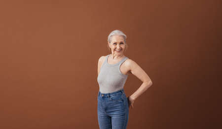 Portrait of a mature woman in casuals standing at brown background in studioの写真素材