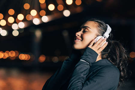 Woman in sports clothes with headphones enjoying music during trainingの写真素材