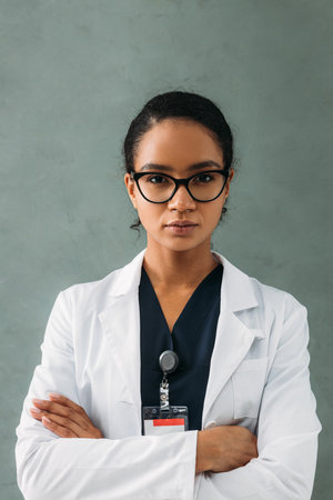 Female medical worker standing against grey background