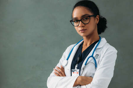 Young confident doctor in a lab coat with stethoscope looking at camera