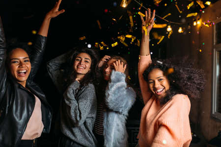 Night party on a terrace. Happy women having fun under confetti.の写真素材