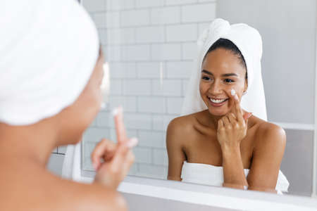 Beautiful mixed race woman looking at her reflection in mirrorの写真素材