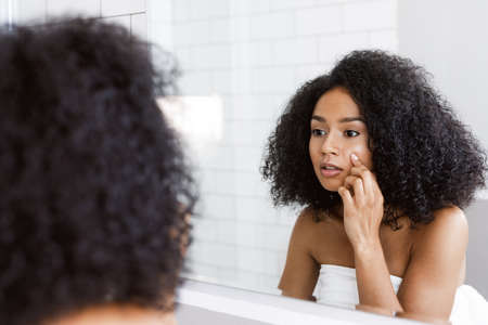Beautiful mixed race woman looking at her reflection in mirrorの写真素材