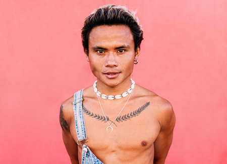 Portrait of a smiling handsome guy in casuals standing at pink wallの写真素材