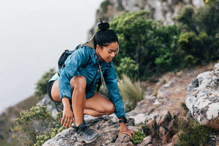 Back view of a woman in hiking sportswear standing on a cliff at sunset. Sportswoman looking at the ocean on the top of the mountain.の写真素材