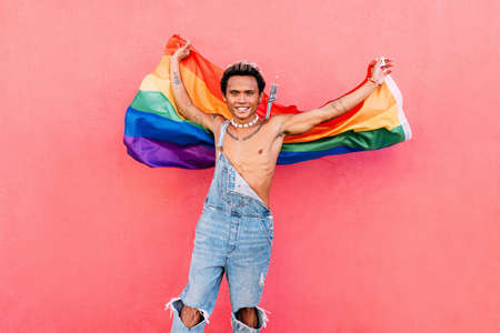 Portrait of a young happy guy with rainbow LGBT flag looking at camera
