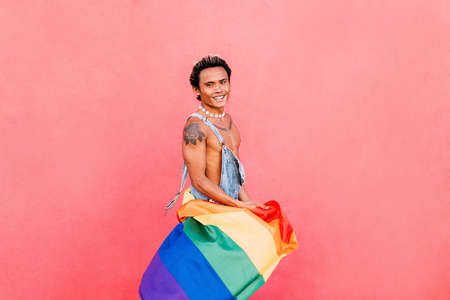 Portrait of a young handsome guy with bare chest looking at camera at pink wallの写真素材