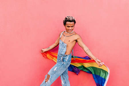 Portrait of a young handsome guy with bare chest looking at camera at pink wallの写真素材