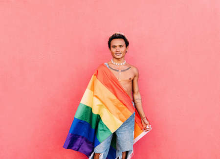 Young stylish guy in casuals dancing at pink wall and looking at cameraの写真素材